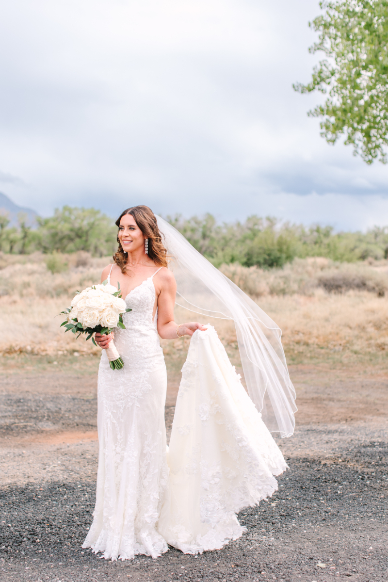 Bride stands holding the bottom of her dress for portraits.