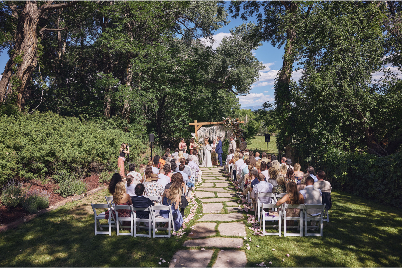 Tennessee Highlands wedding ceremony with boho decor including white folding chairs, wooden arch with macrame design and dusty pink florals.