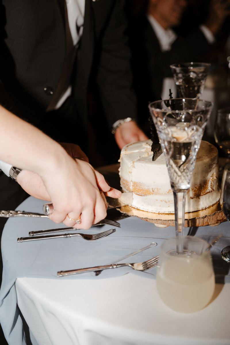 Bride and groom cut cake together during their wedding reception.