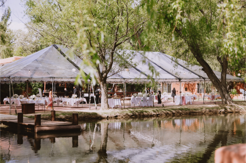 Tented wedding reception set up next to pond.