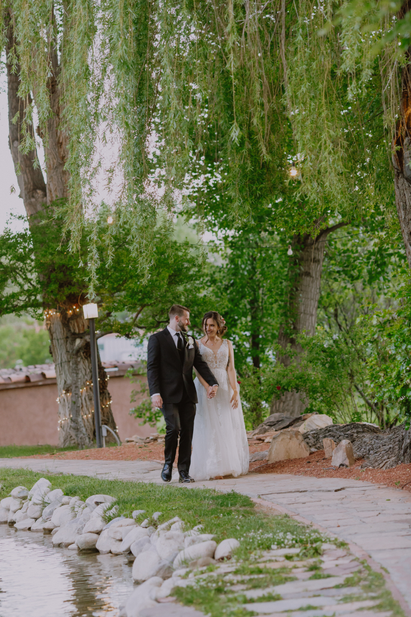 Bride and groom walk together along sidewalk at Nashville wedding venues on-site pond.