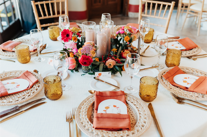 Round wedding reception table with large candles sitting inside wildflower centerpiece.