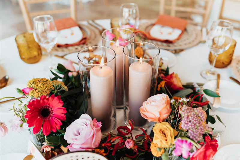 Three votive candles surrounded by colorful wildflower arrangement for wedding reception in New Mexico.