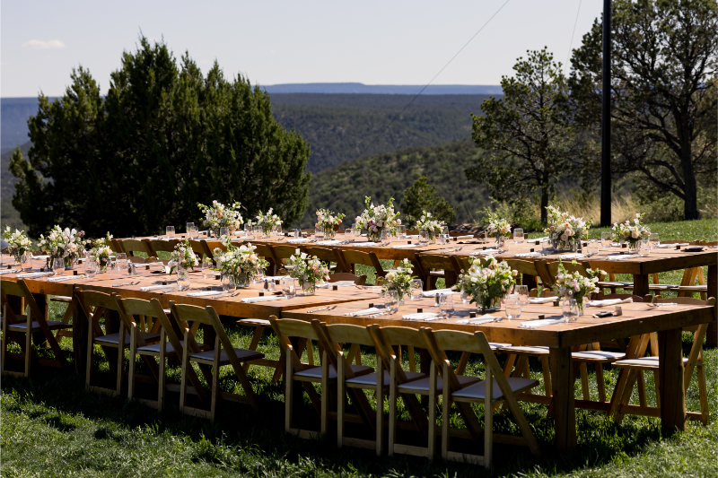 Long rectangular reception table decorated with seasonal wildflower centerpieces.