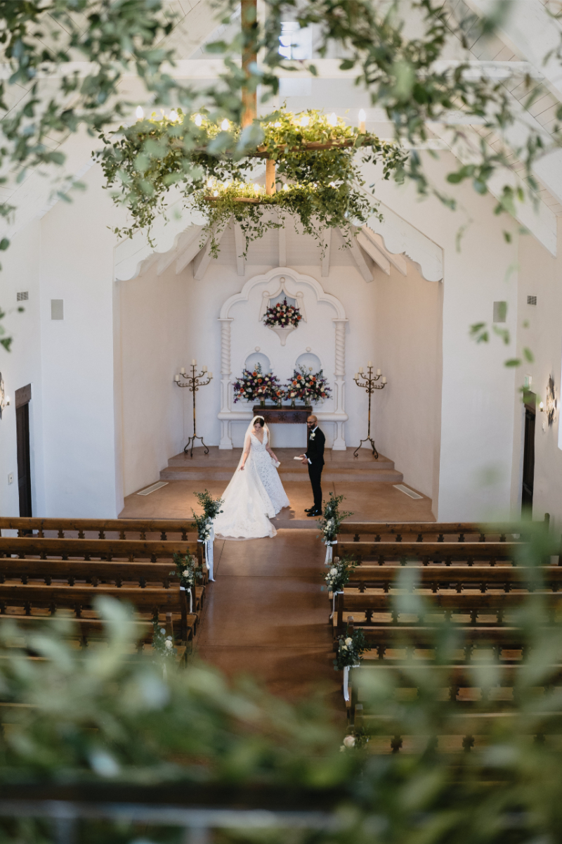 Bride and groom share private vows inside a chapel before their desert garden botanical wedding, greenery framing them in the image.
