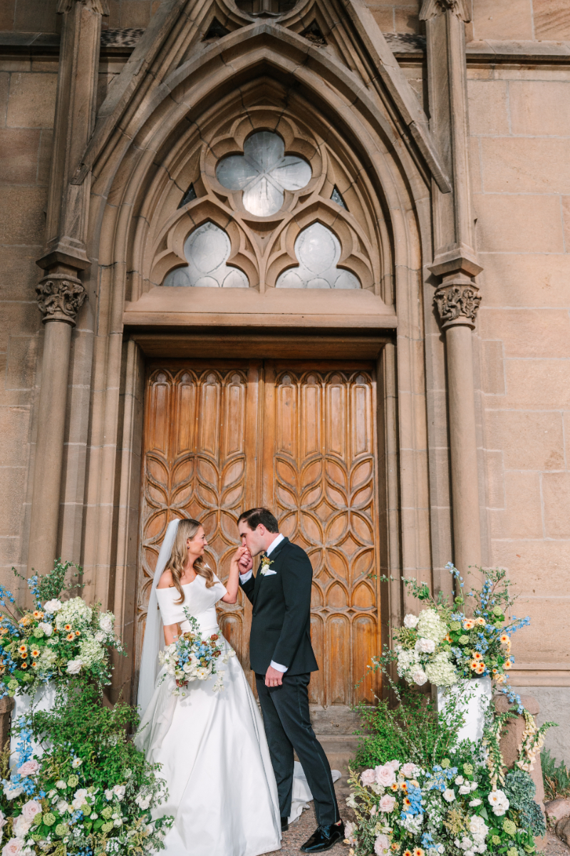 Bride and groom portrait at Tennessee wedding venues featuring Gothic stone architecture, carved wooden doors, and lush blue and white floral installations.