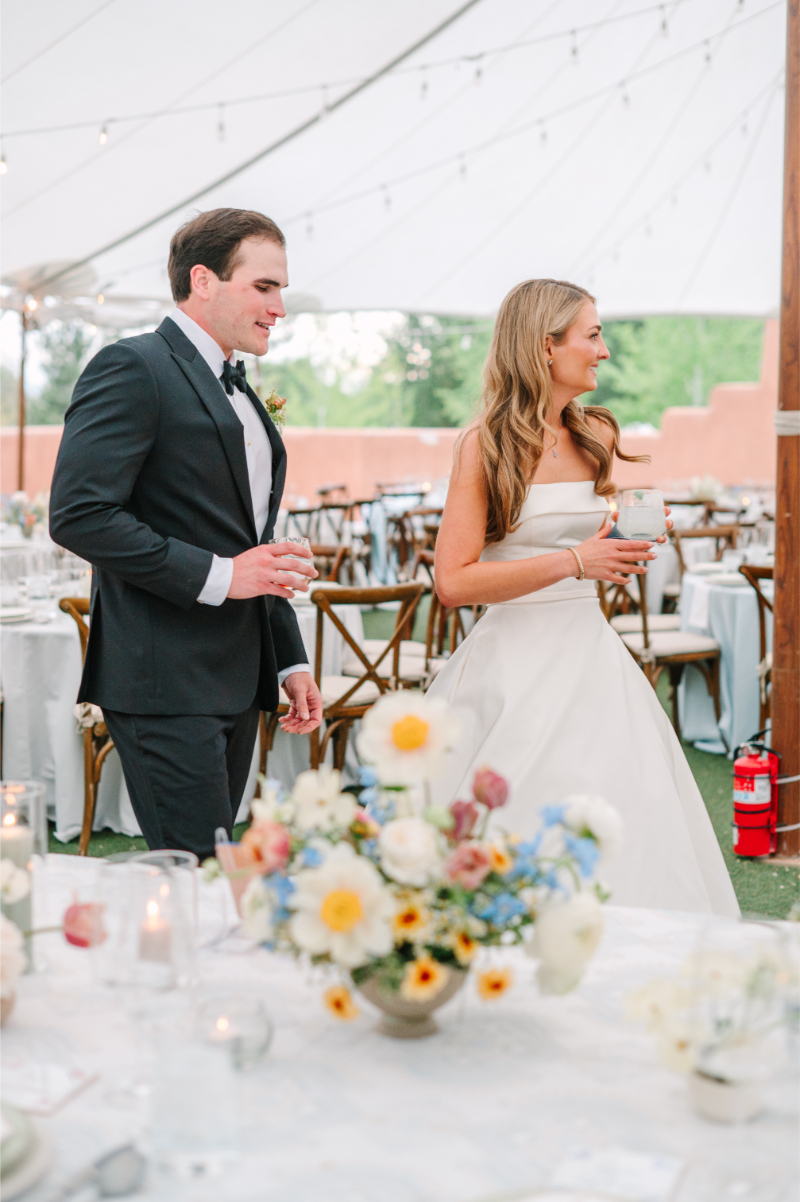 Couple at Tennessee wedding venues tented reception with wildflower centerpieces of white daisies, blue delphinium, and soft pink blooms.