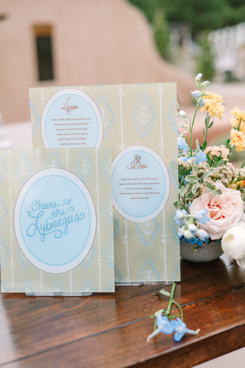 Custom bar menu and drink signage with calligraphy script displayed beside a garden floral arrangement at a Tennessee wedding venues reception.