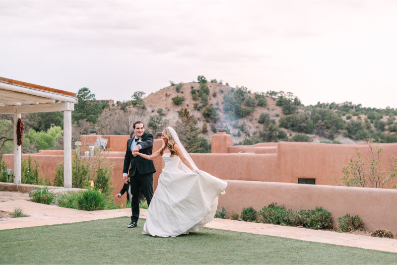 Bride and groom dancing on the lawn at Tennessee wedding venues with adobe architecture and mountain views in the background.