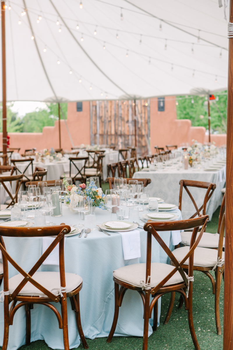 Tented outdoor reception at Tennessee wedding venues with pale blue linens, crossback chairs, string lights, and garden floral centerpieces.