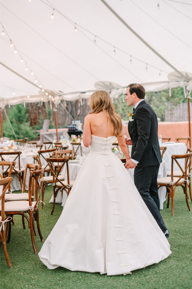 Bride and groom entering their tented reception at Tennessee wedding venues with string lights and soft blue table settings.