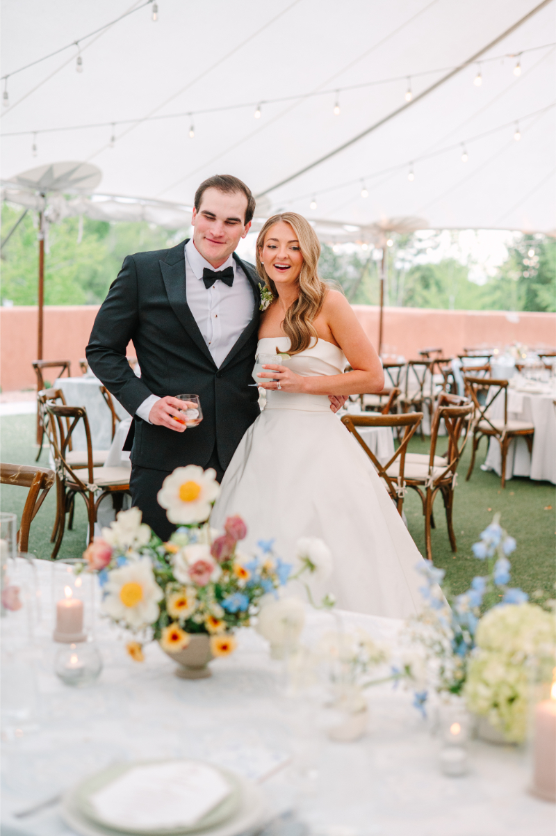 Bride and groom smiling at their Tennessee wedding venues tented reception with colorful garden floral centerpieces and candlelight.