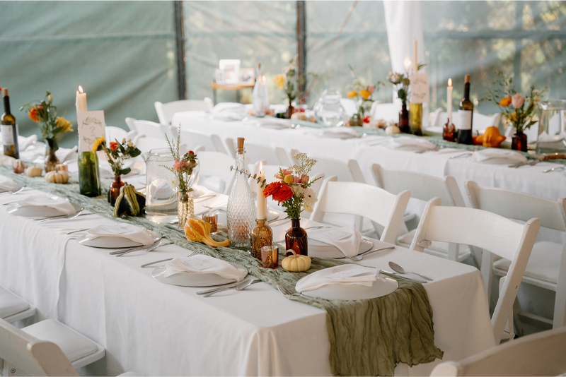 Rectangle reception tables lined with amber bud vase centerpieces for a celebration in New Mexico.