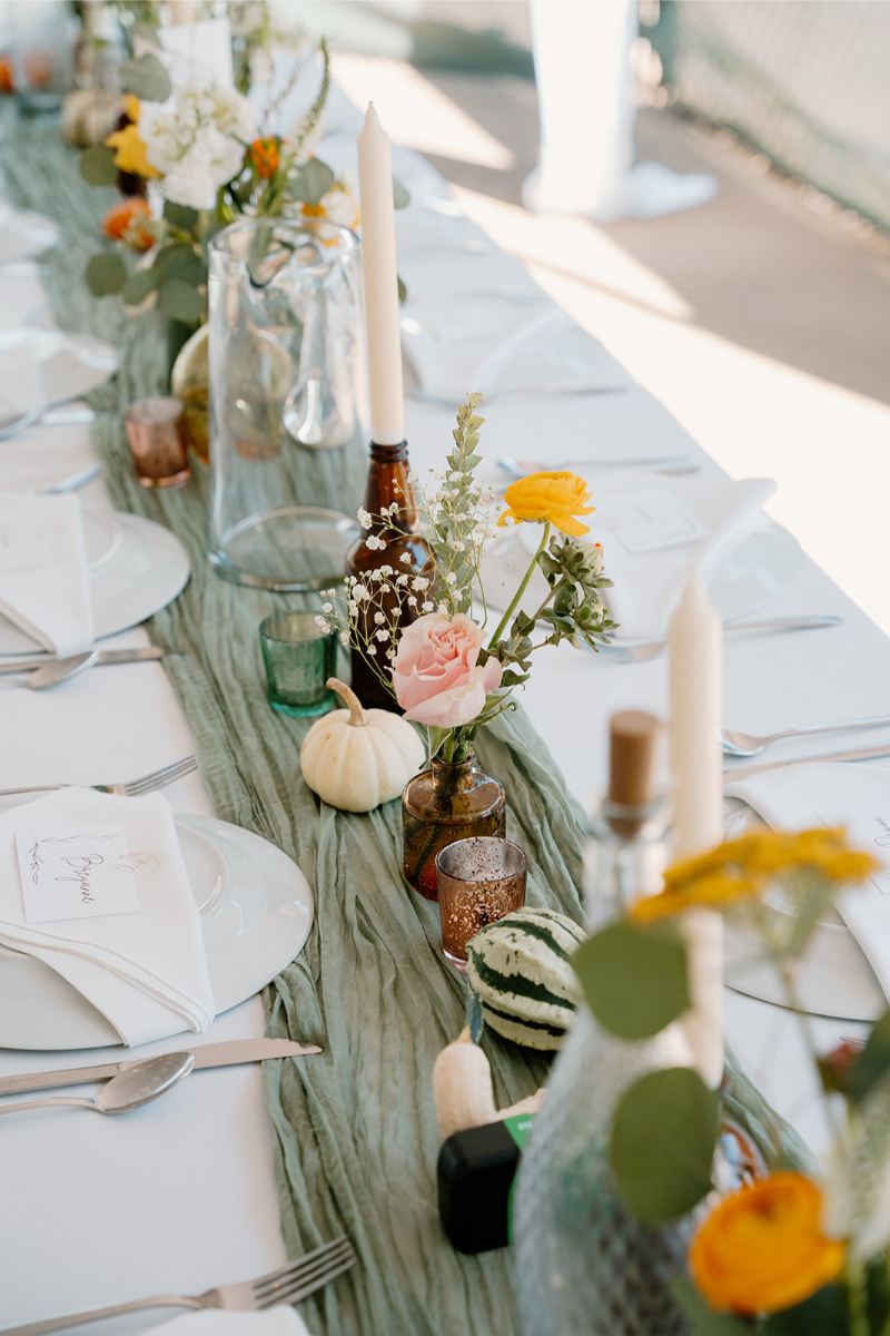 Amber bud vases and taper candles arranged for a New Mexico wedding reception tablescape.