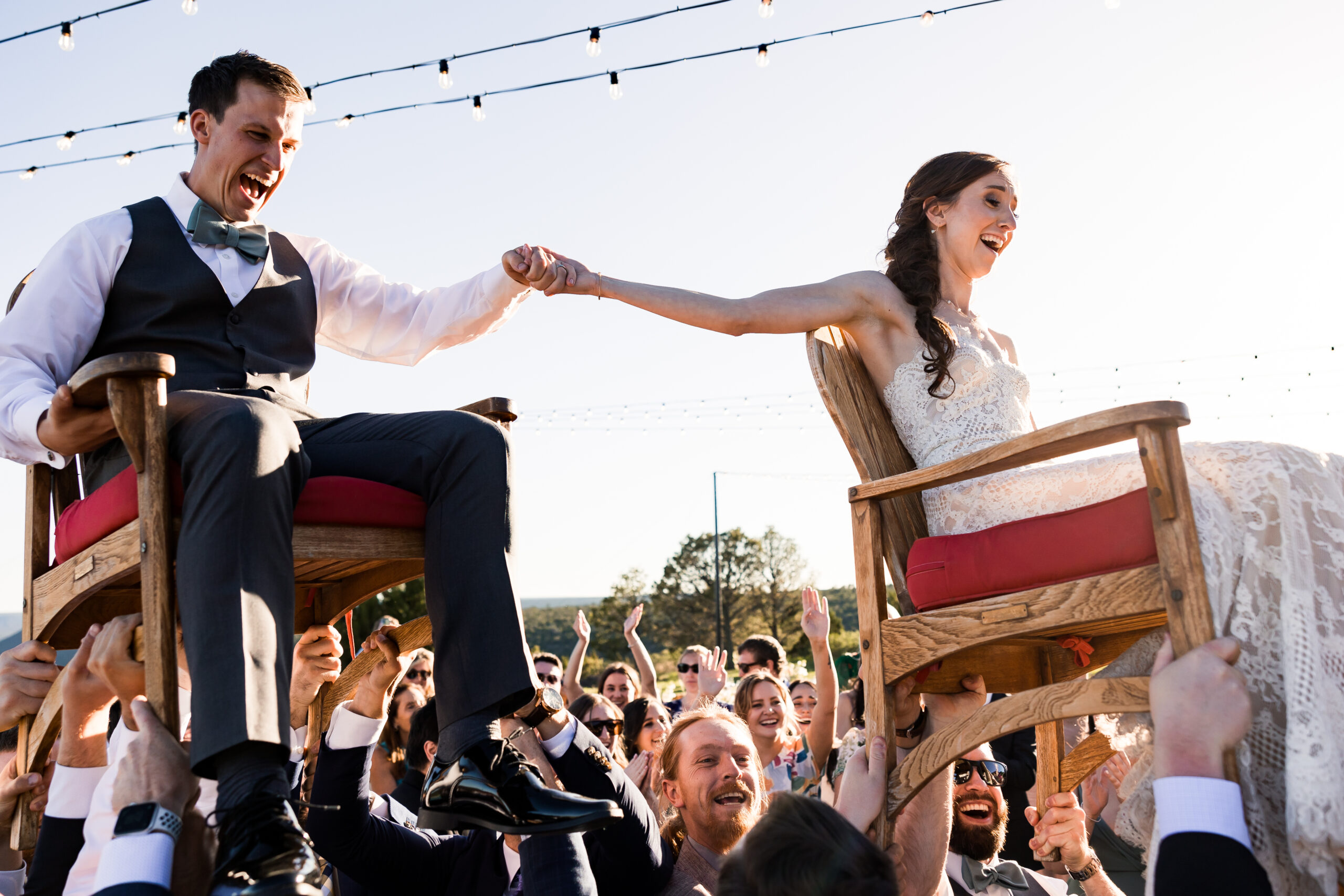Bride and groom are lifted into the air in their seats on the dance floor during a wedding reception.