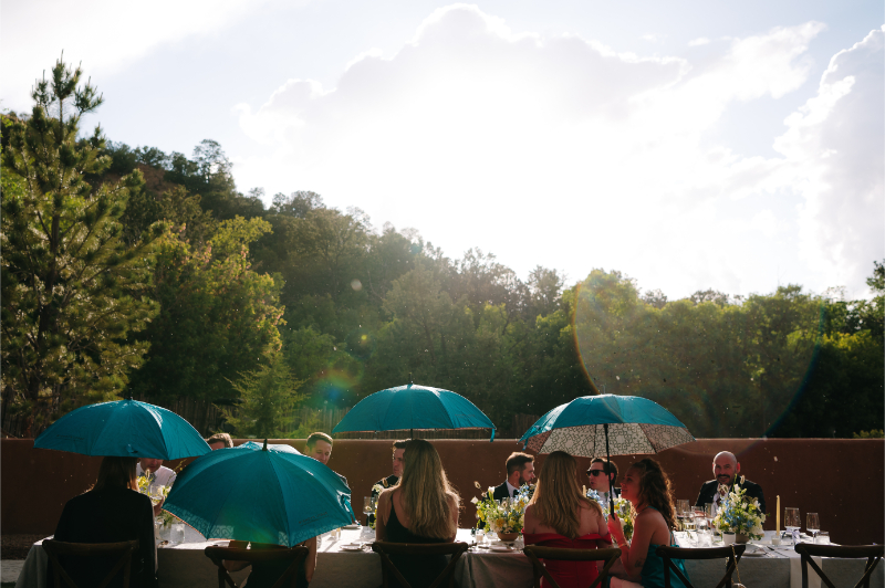 Guests hold turquoise umbrellas to shade themselves from the New Mexico sun in the Fall.