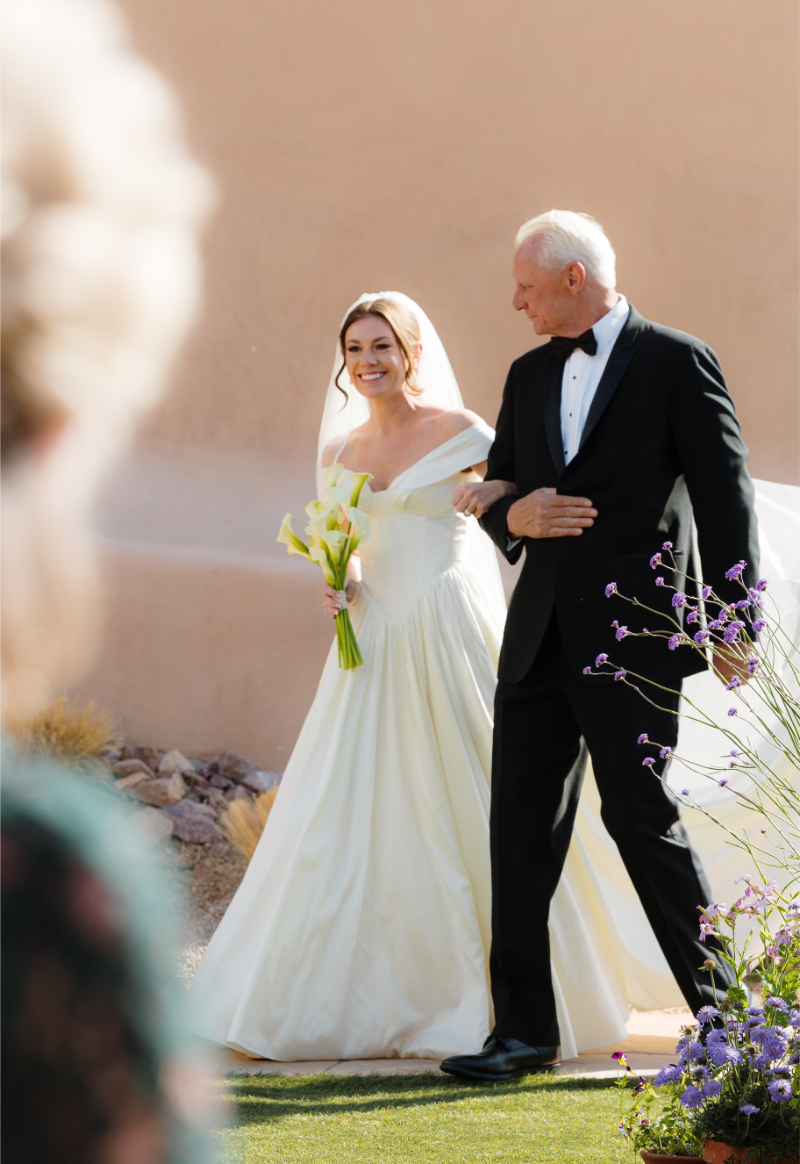 Bride turns the corner of the aisle with her dad leading her.