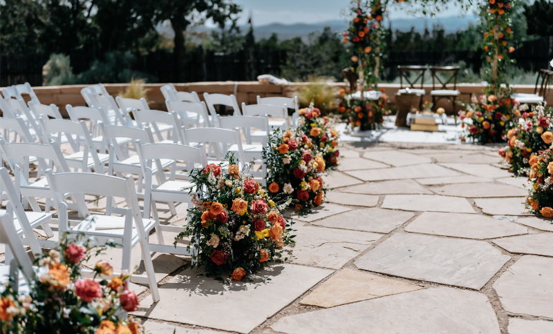 Colorful floral arrangements line the aisle for a wedding ceremony.