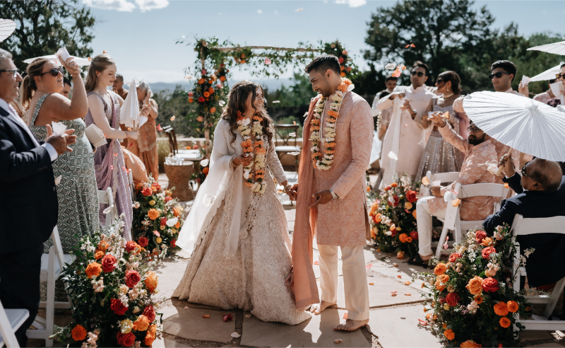 Bride and groom holding hands and smiling as they exit their wedding ceremony.