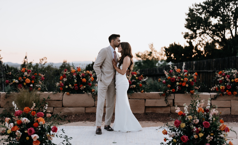 Groom kisses bride on the forehead as they pose for portraits in the ceremony space at Pat's Summitt wedding venue in Jasper Highlands, Tennessee.