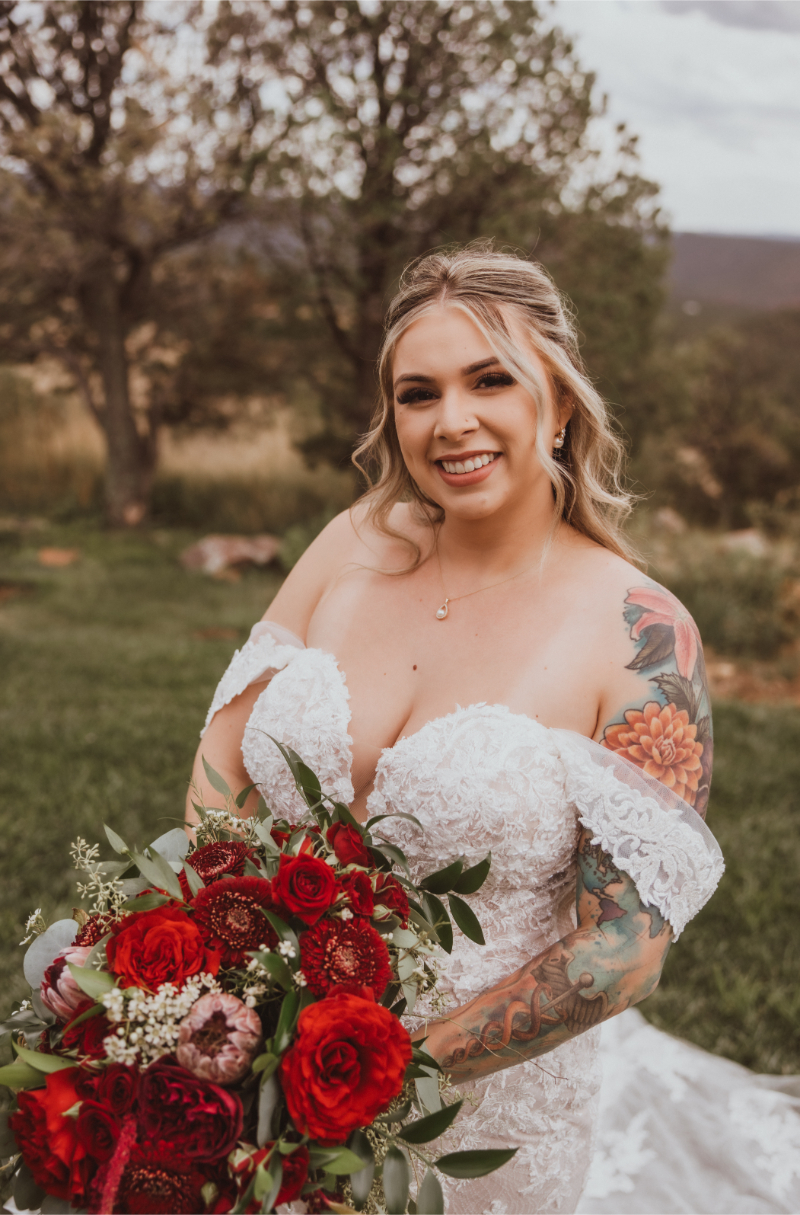 Winter bride stands holding cascading red bouquet, one of her most requested Christmas wedding ideas.