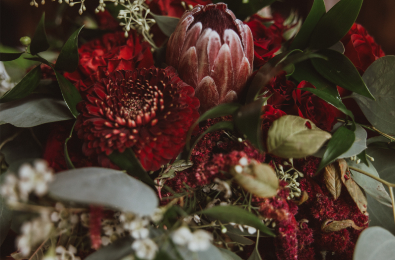 Closeup of wedding bouquet with several shades of red and green, one of the bride's Christmas wedding ideas brought to life.