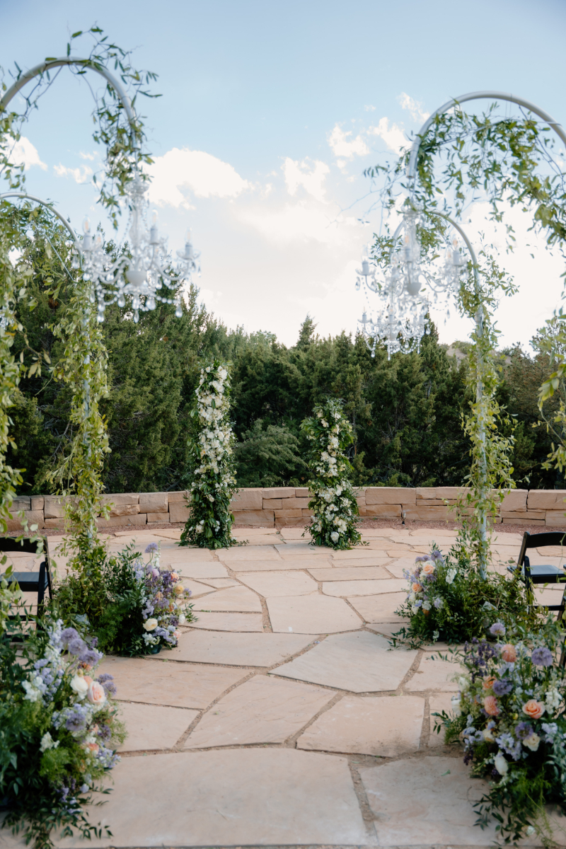 Arched floral arrangements line aisle, showing how many different wedding arch ideas there are.