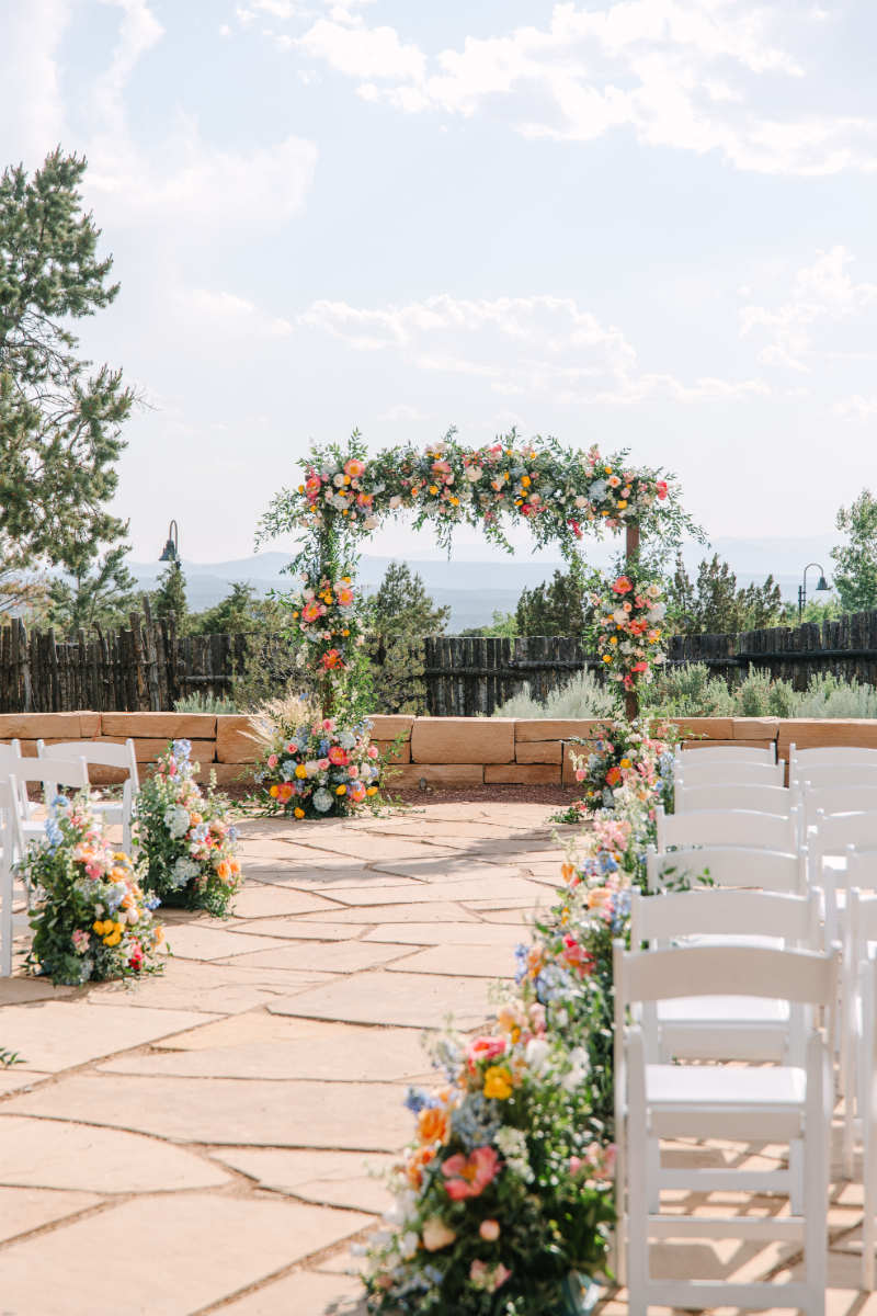 Floral arrangements lining an aisle with a large floral arch at the altar.