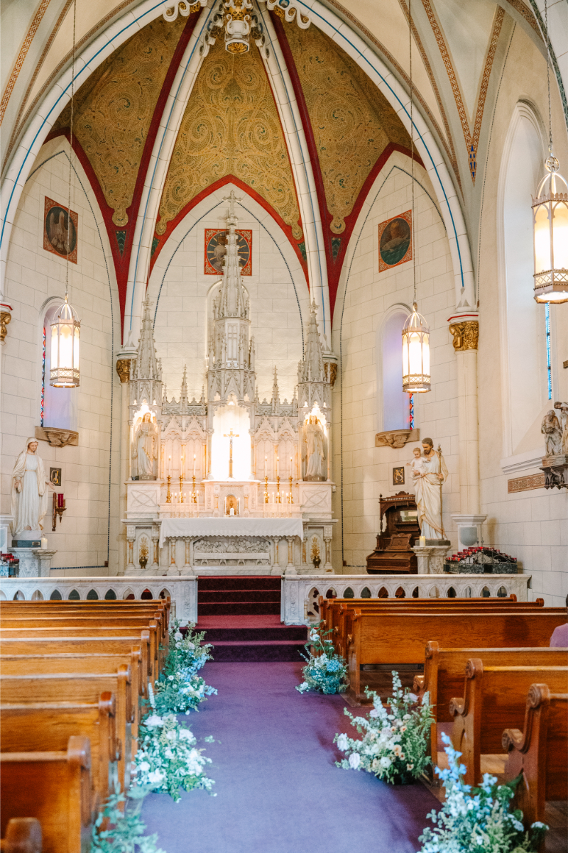 The altar and seats decorated for a church ceremony with ground floral arrangements.