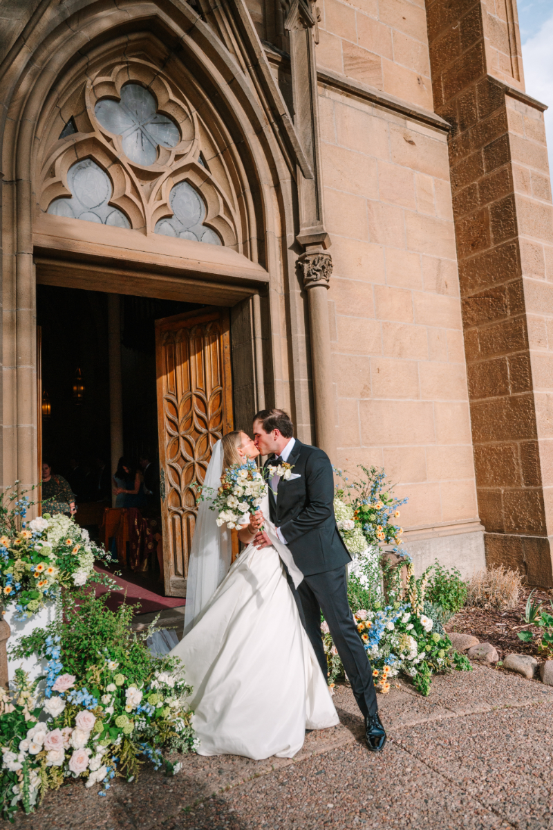 Bride and groom kiss at the entrance of the church as they exit their wedding ceremony.
