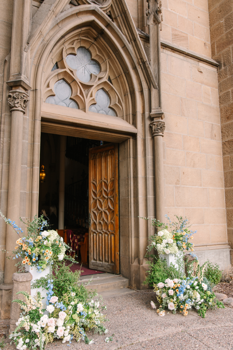 One of the best wedding ceremony ideas is to decorate the entrance where guests get their first impression of whats to come. This church entrance is decorated with two cascading floral arrangements down the steps.