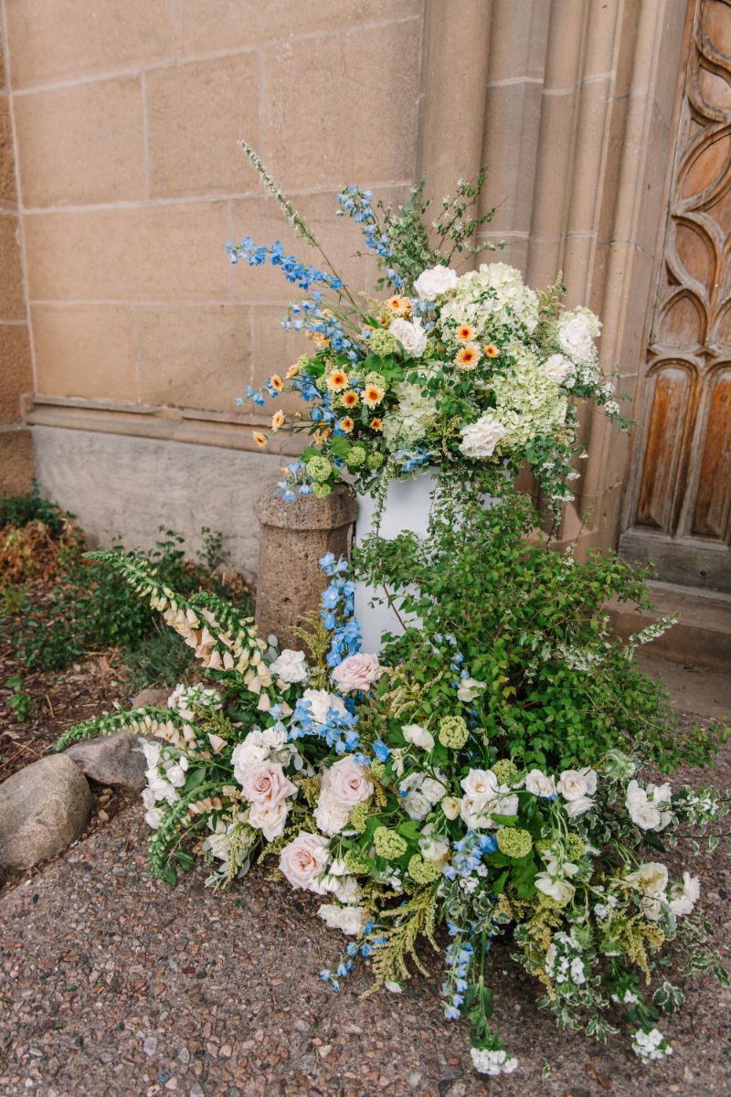 Floral arrangements sitting at the base of church entrance for a wedding ceremony.