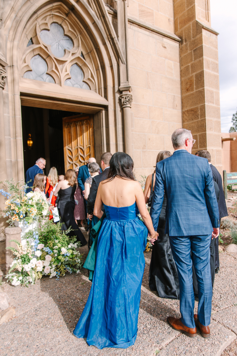 Girl hands out wedding ceremony stationery as guest enter church.