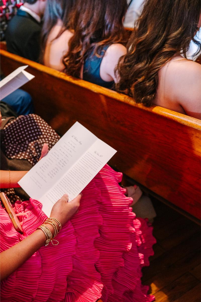 Guest reads ceremony stationery before church procession starts.