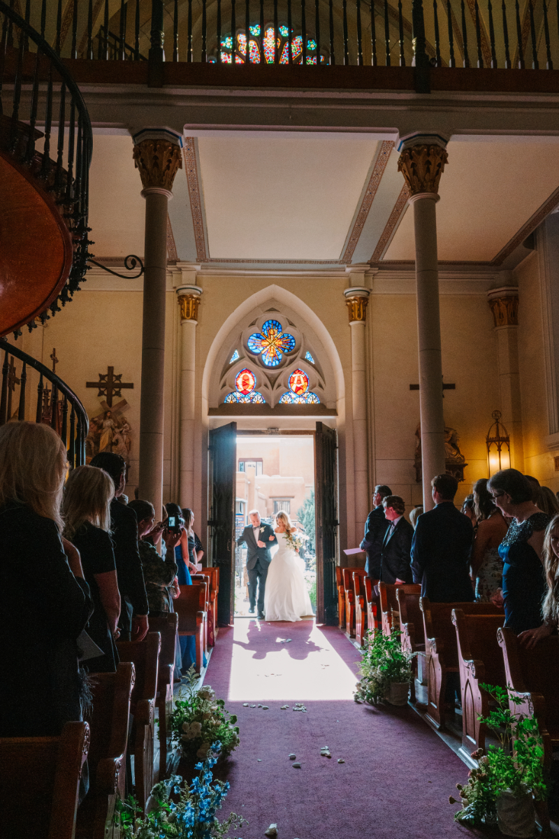 Bride walks into church, escorted by her father, to the altar.