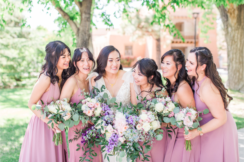 Bride is surrounded by her bridesmaids as they wear pink dresses.